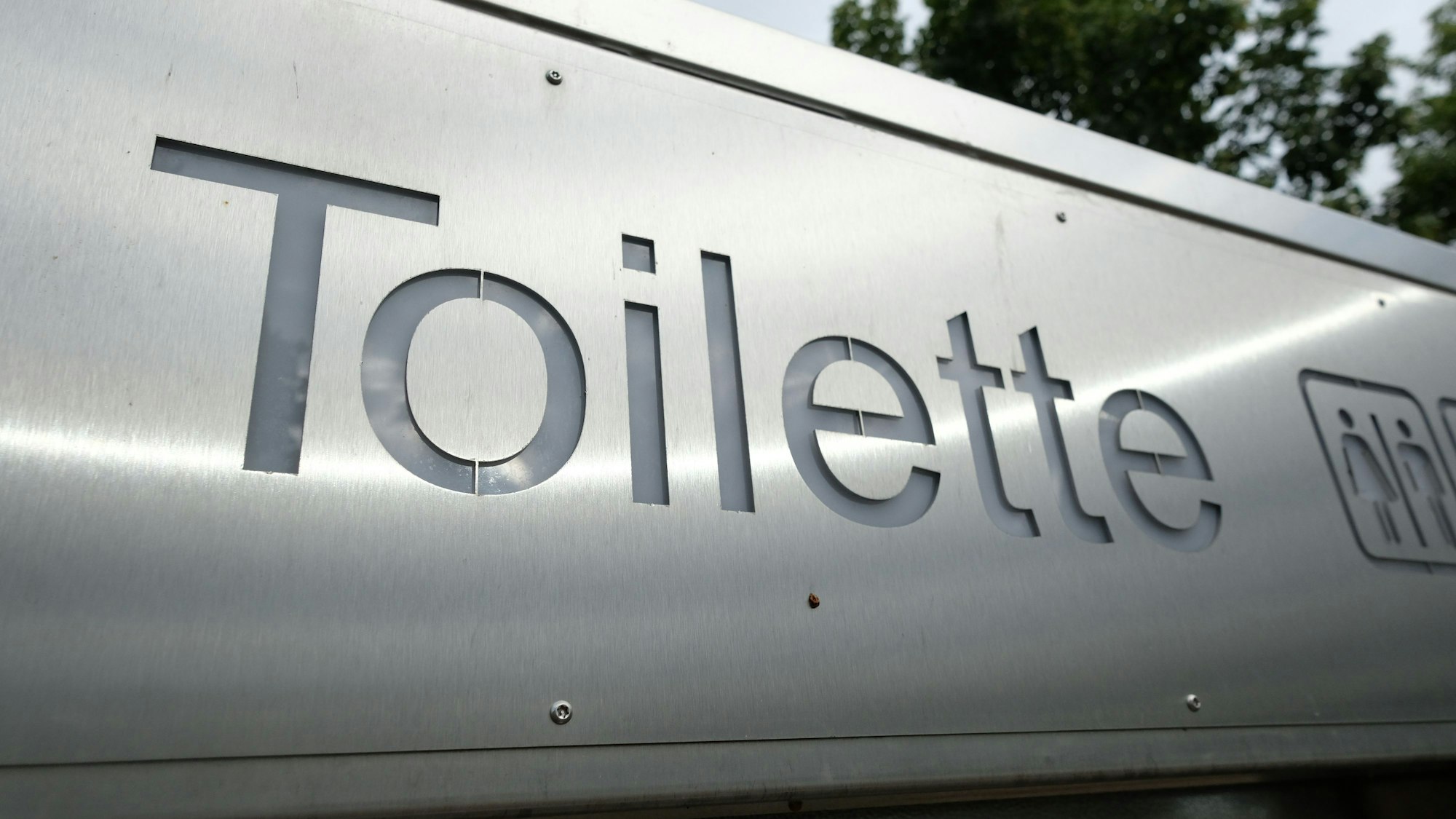 Ein Schild weist in der Innenstadt den Weg zu einer öffentlichen Toilette.