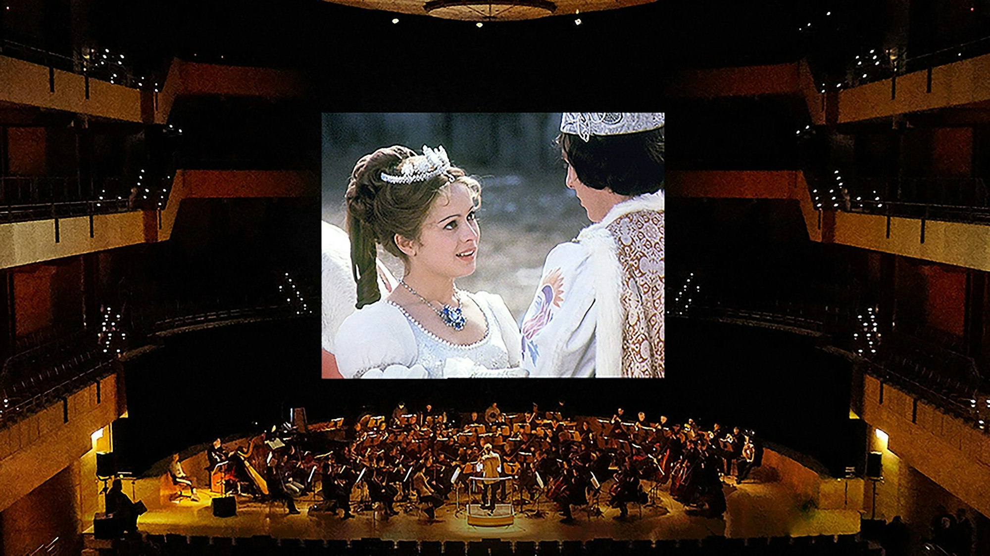 Ein Orchester spielt, während der Film auf der Leinwand läuft.