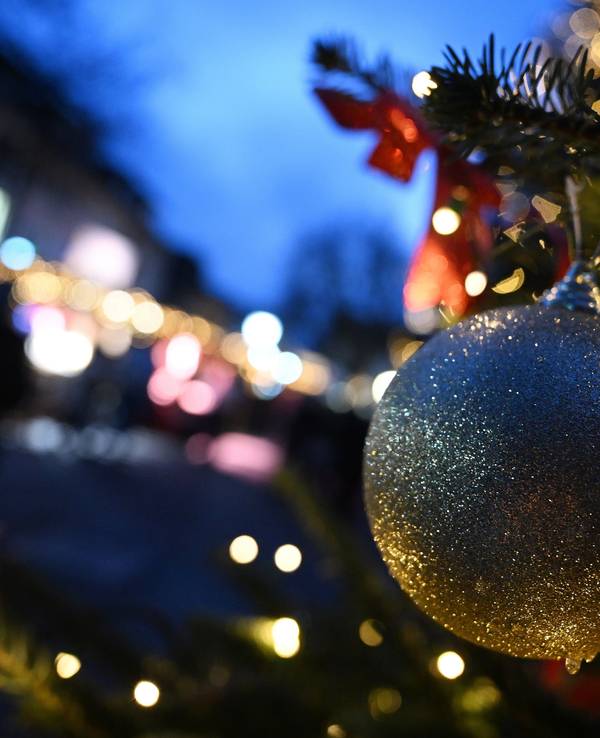 Das Symbolfoto zeigt eine goldene Weihnachtsbaum-Kugel, im Hintergrund sind Tannengrün und Lichter zu sehen.