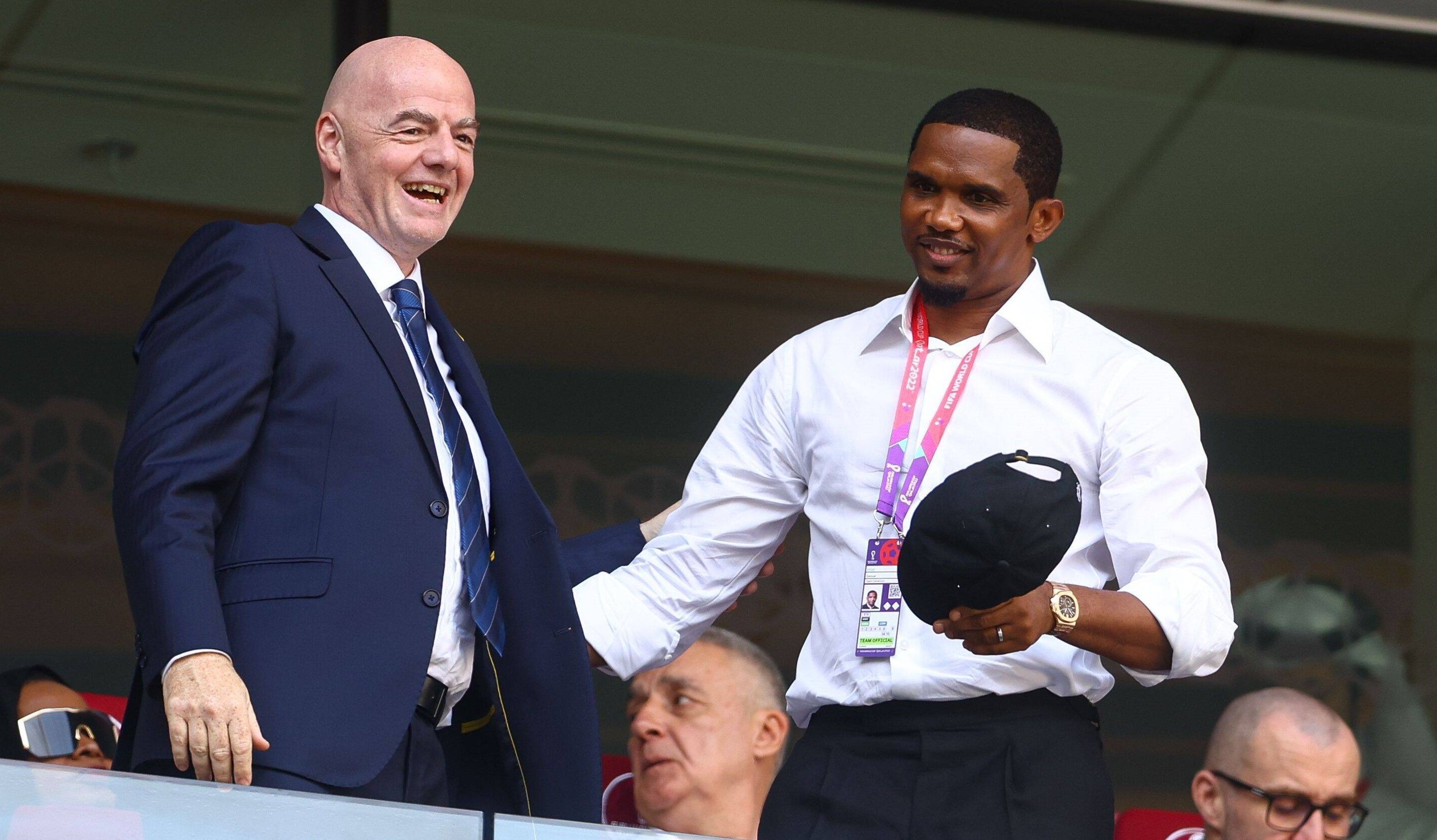 Samuel Eto'o steht beim WM-Spiel zwischen Kamerun und Serbien neben FIFA-Präsident Gianni Infantino und lächelt