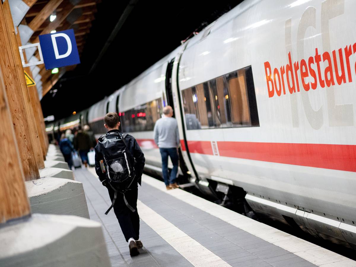Fahrgäste gehen am frühen Morgen mit ihrem Gepäck über einen Bahnsteig am Hauptbahnhof, um in einen ICE der Deutschen Bahn einzusteigen.