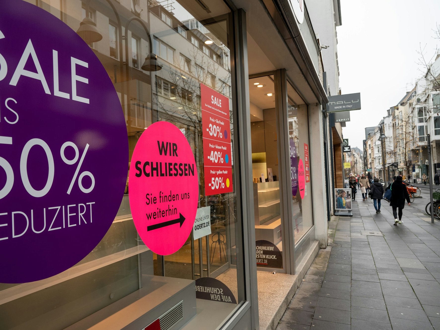 Die Filiale von Görtz auf der Kölner Ehrenstraße von außen. Zu sehen sind unter anderem Aufkleber, auf denen die Schließung des Ladens angekündigt wird.