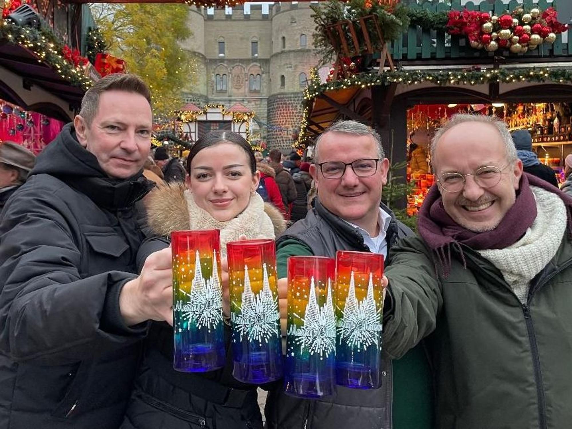 Vier Menschen halten die bunten Glühweintassen in die Kamera.