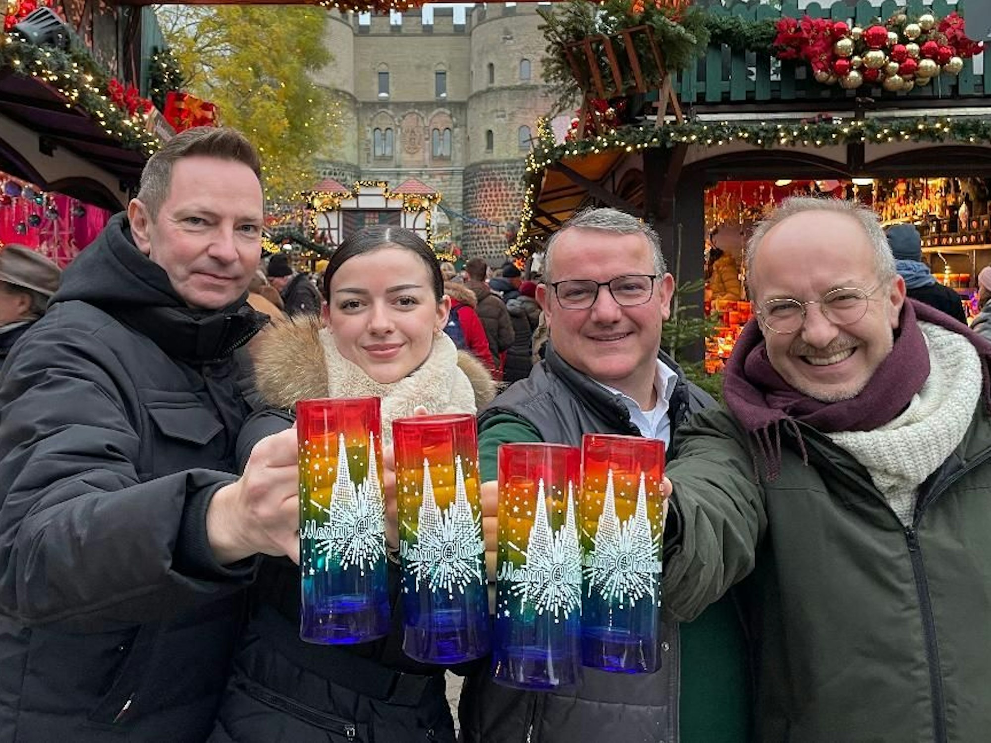 Vier Menschen halten die bunten Glühweintassen in die Kamera.