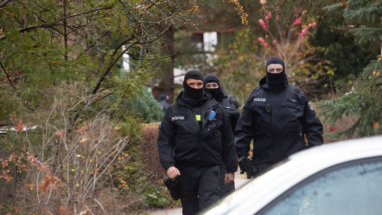 Drei maskierte Polizistinnen und Polizisten laufen in Uniform zu ihrem Auto.