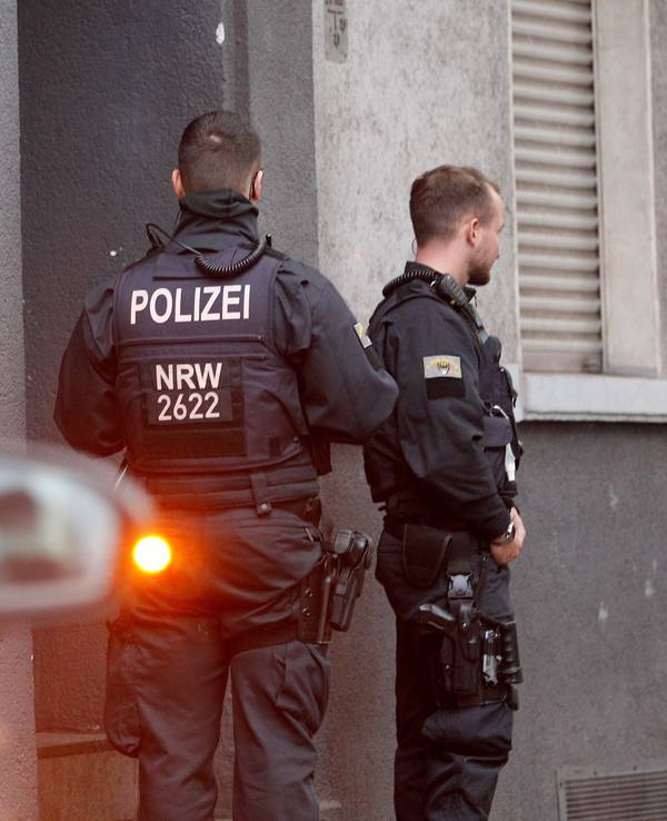 Polizisten stehen vor einem Haus, in dem sie eine Wohnung durchsucht haben.