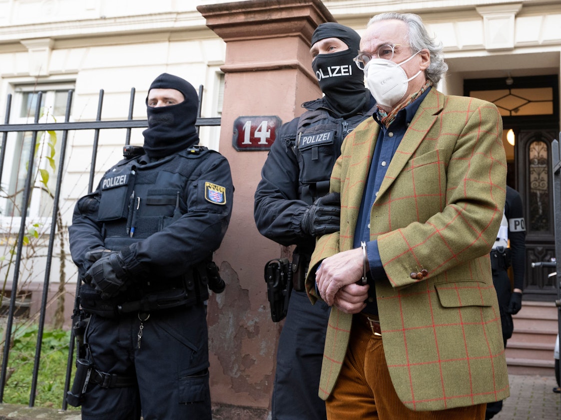Bei einer Razzia gegen sogenannte „Reichsbürger“ führen vermummte Polizisten, nach der Durchsuchung eines Hauses Heinrich XIII Prinz Reuß (r) zu einem Polizeifahrzeug.