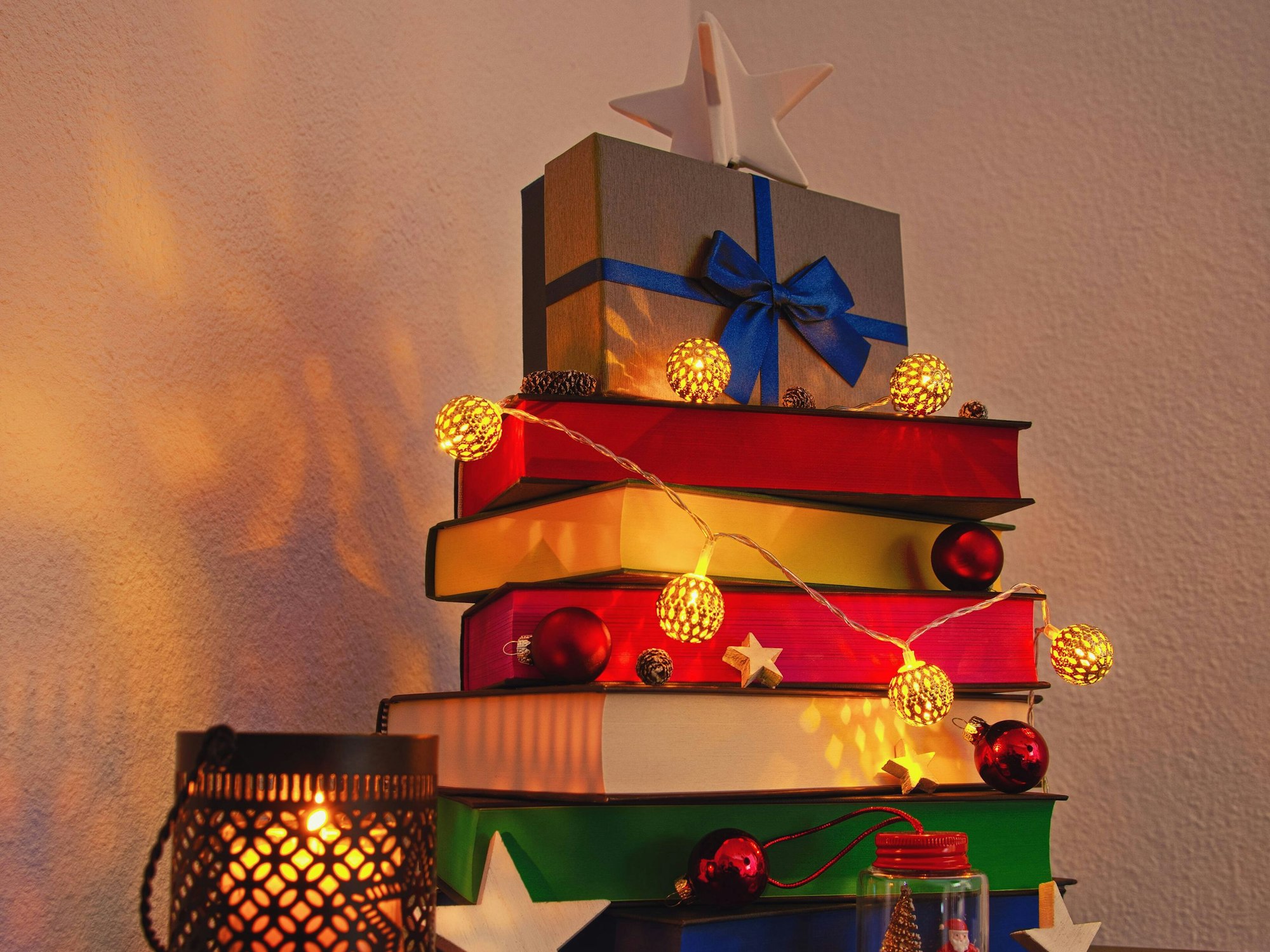 Gestapelte Bücher sind mit einer Lichterkette geschmückt.