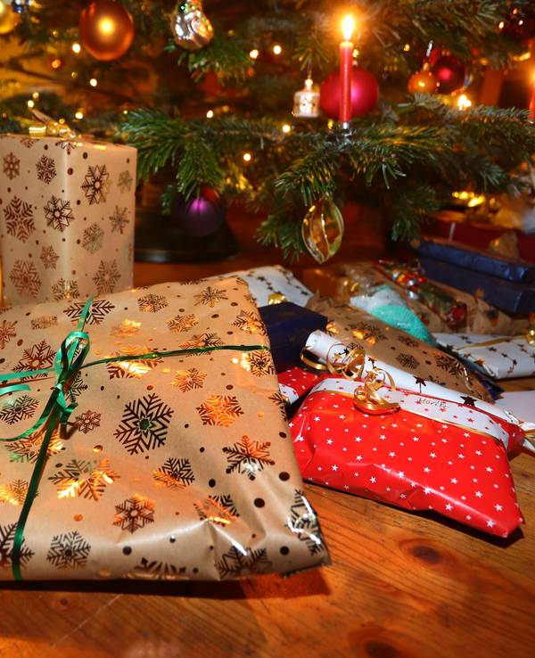 Verpackte Geschenke liegen unter einem festlich geschmücktem Weihnachtsbaum.