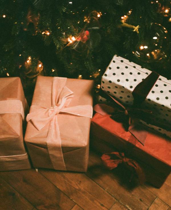 Unter einem Tannenbaum liegen mehrere verpackte Geschenke.