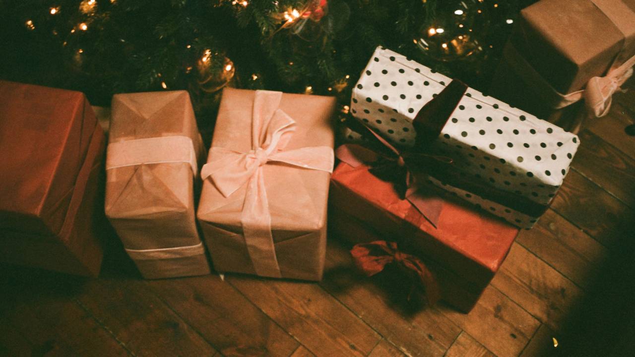 Unter einem Tannenbaum liegen mehrere verpackte Geschenke.