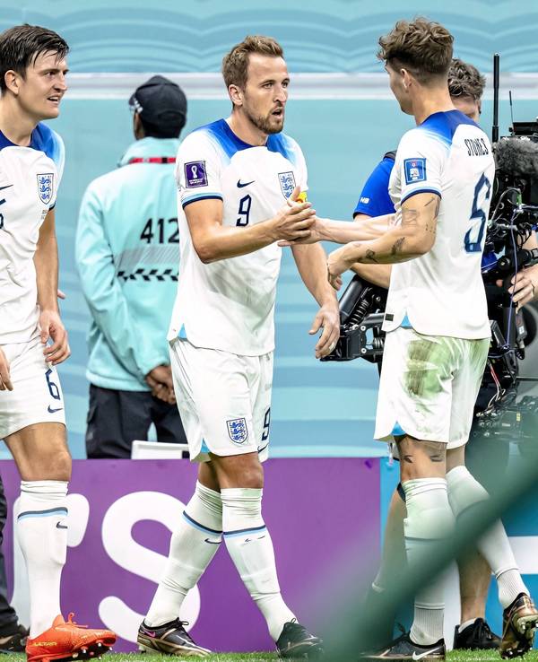 Harry Maguire (l.) und John Stones (r.) jubeln mit Englands Torschütze Harry Kane nach dessen 2:0 im WM-Achtelfinale von Katar gegen den Senegal.