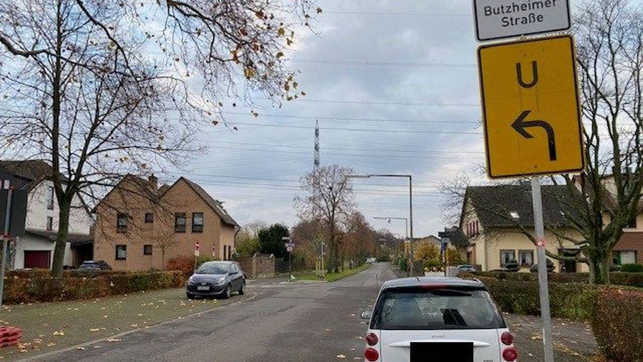 Ein Smart steht an einer Straße vor einem Schild, das auf eine Umleitung hindeutet.