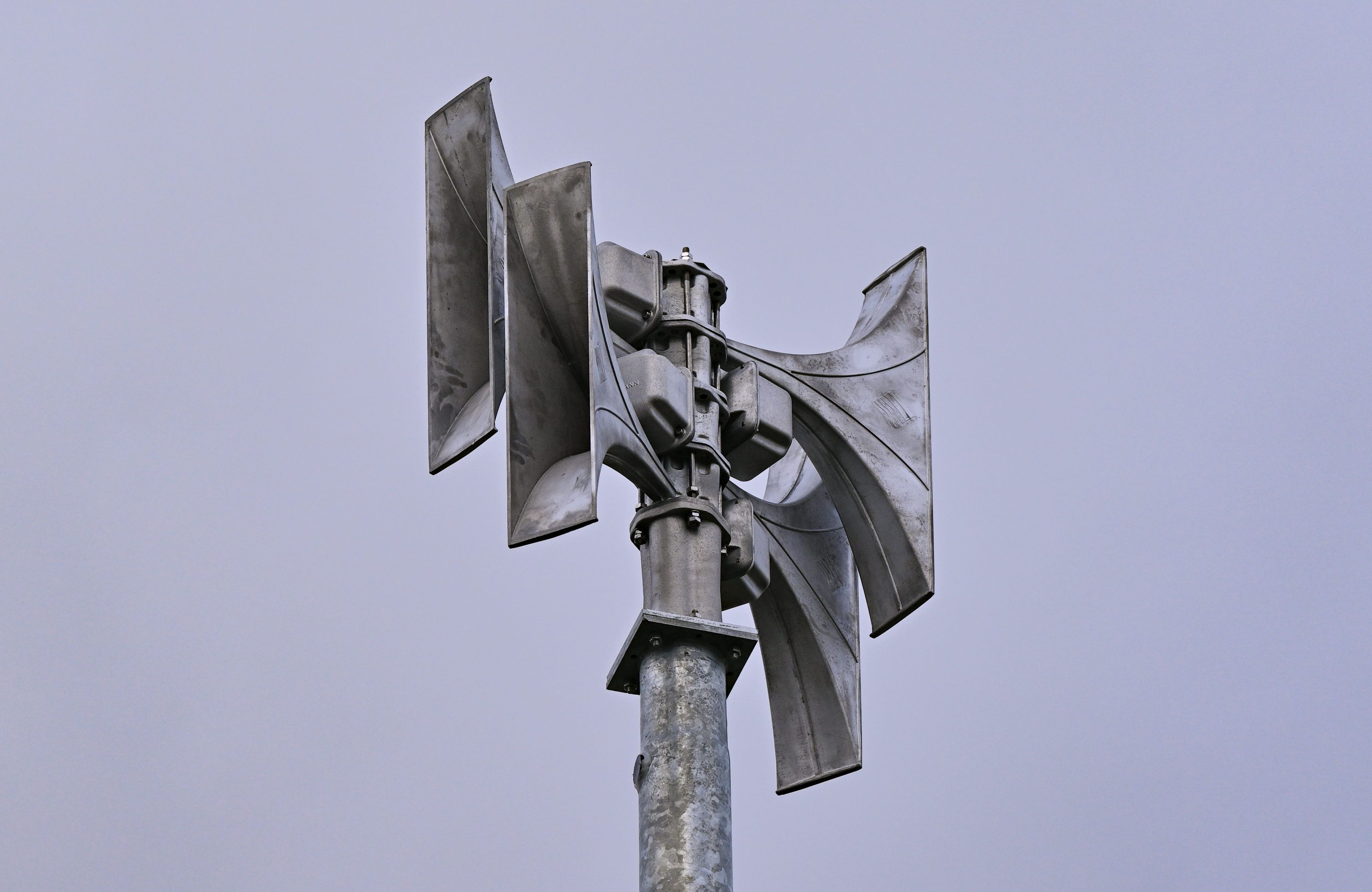 Eine Sirene aus Metall vor blauem Himmel.