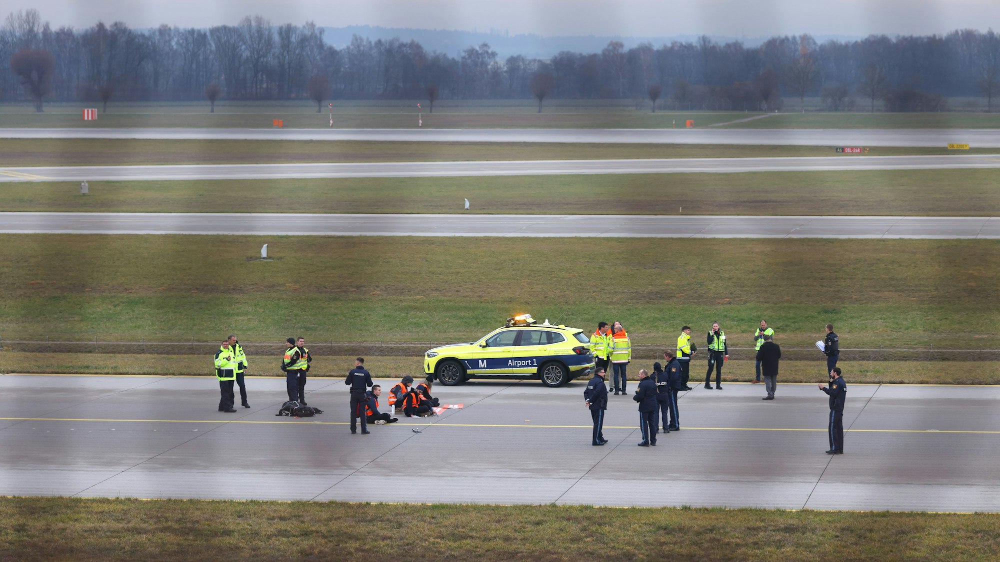 Vier Klimaaktivisten sitzen mit angeklebten Händen auf dem Zubringer einer Start- und Landebahn am Airport Franz-Josef-Strauß.