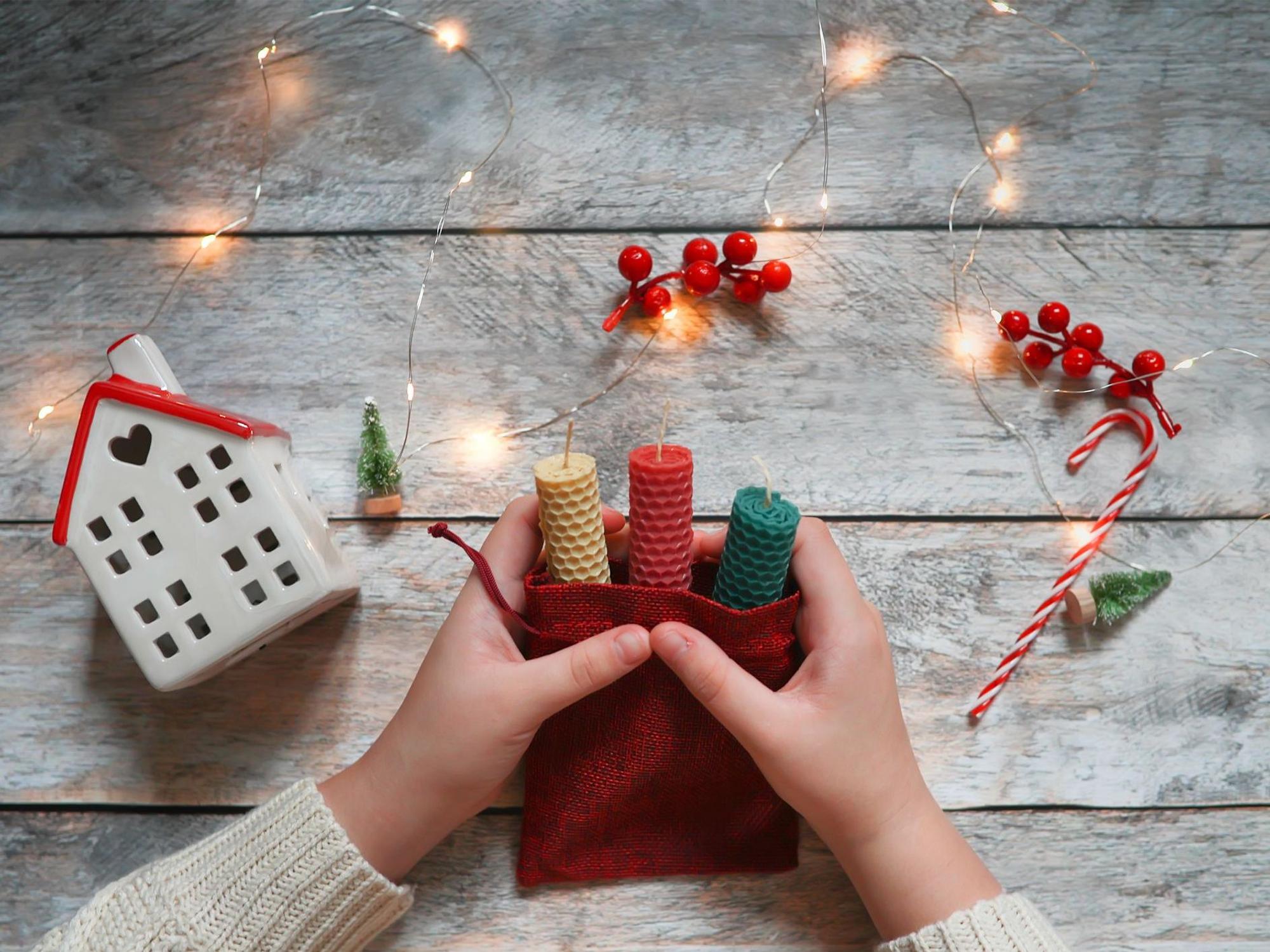 Kinderhände beim Einpacken von Geschenken. 2022 sind zu Weihnachten Selbstgemachtes und Nachhaltiges angesagt.