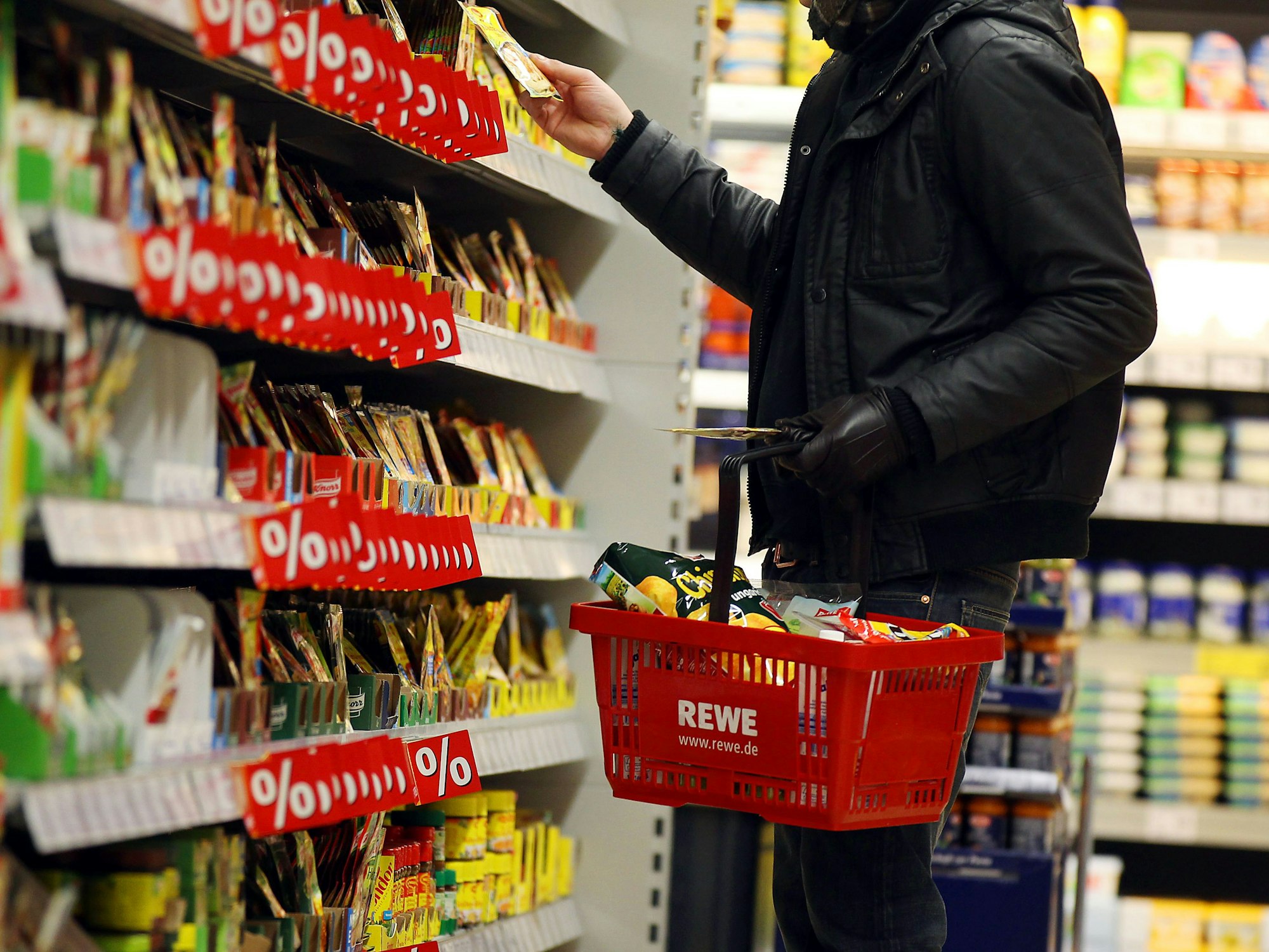 Ein Kunde steht in Köln in einem Rewe-Supermarkt an einem Regal.