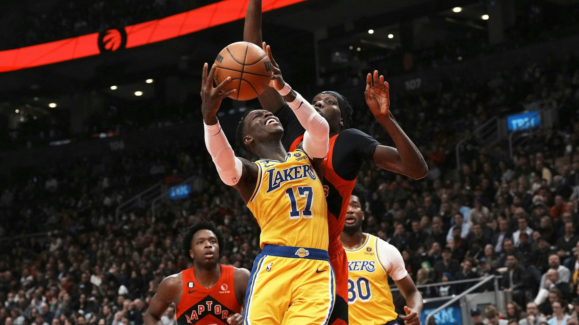 Dennis Schröder im gelben Trikot der Los Angeles Lakers geht zum Korb, während Chris Boucher von den Toronto Raptors verteidigt.