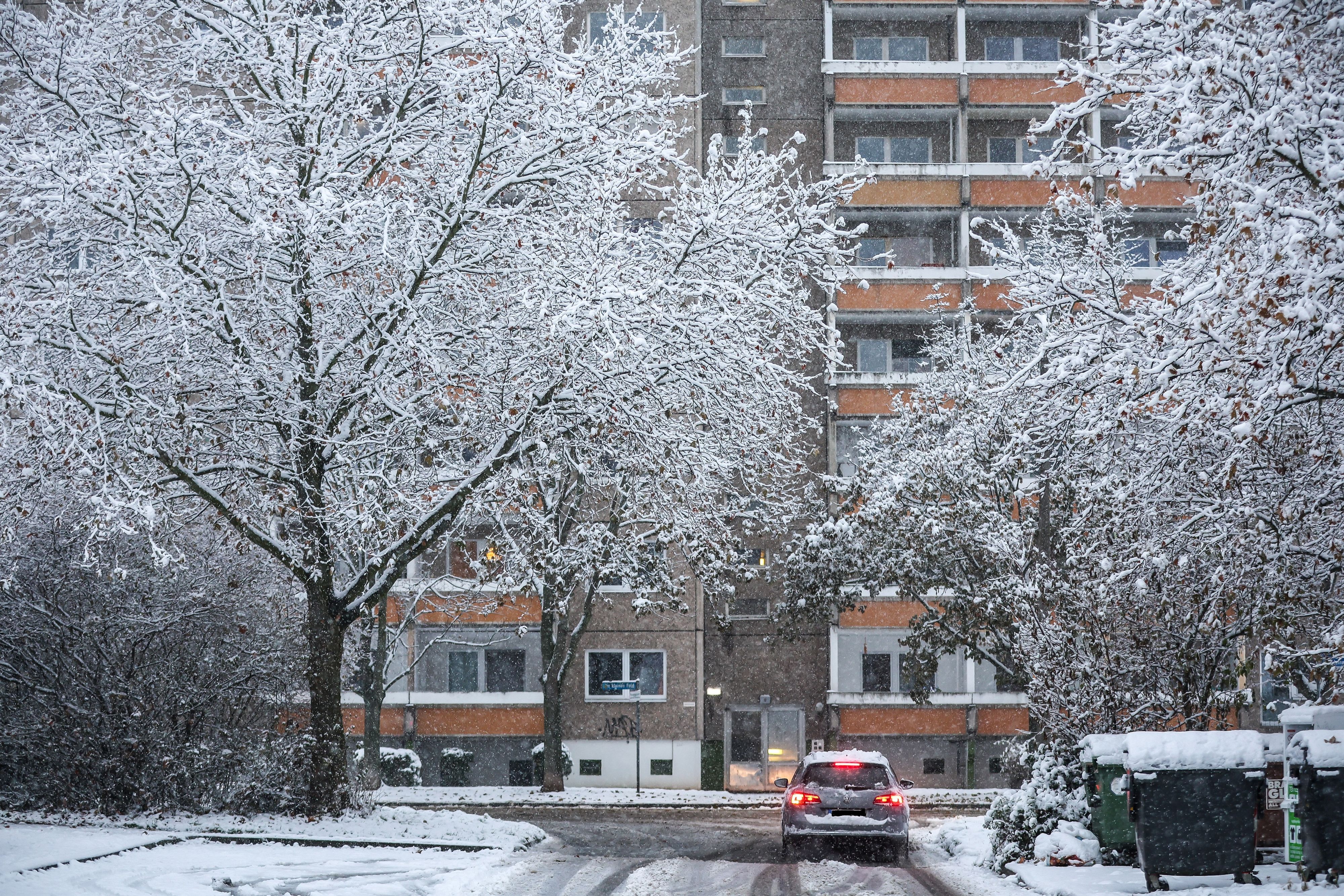 Ein Auto fährt über eine verschneite Straße im Leipziger Stadtteil Grünau.