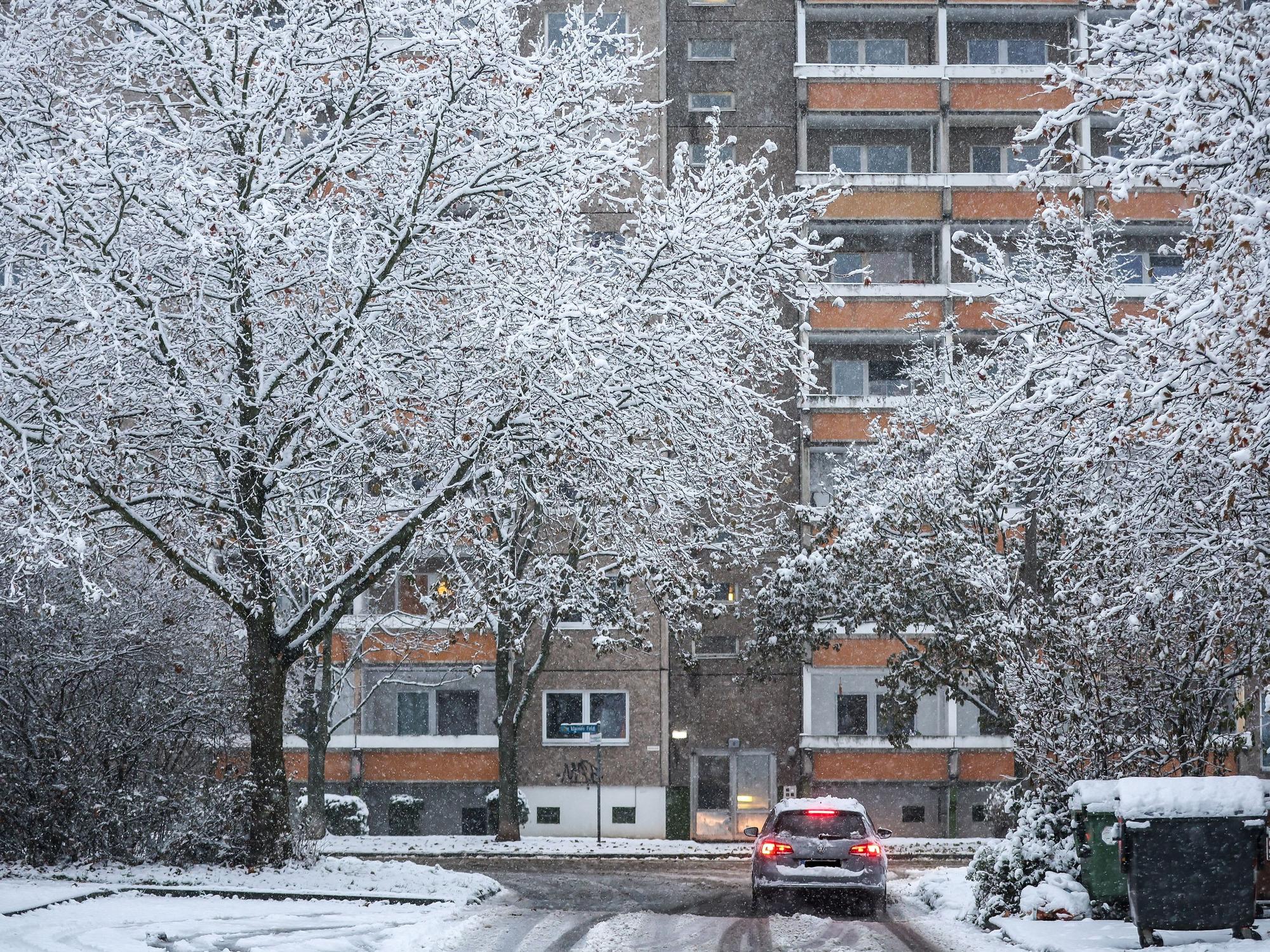 Ein Auto fährt über eine verschneite Straße im Leipziger Stadtteil Grünau.