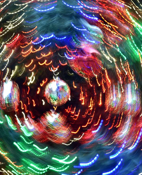 Das Symbolfoto zeigt Weihnachtsbaumkugeln, die sich bewegen. Durch die Langzeitbelichtung entstehen bunte Lichtstreifen.