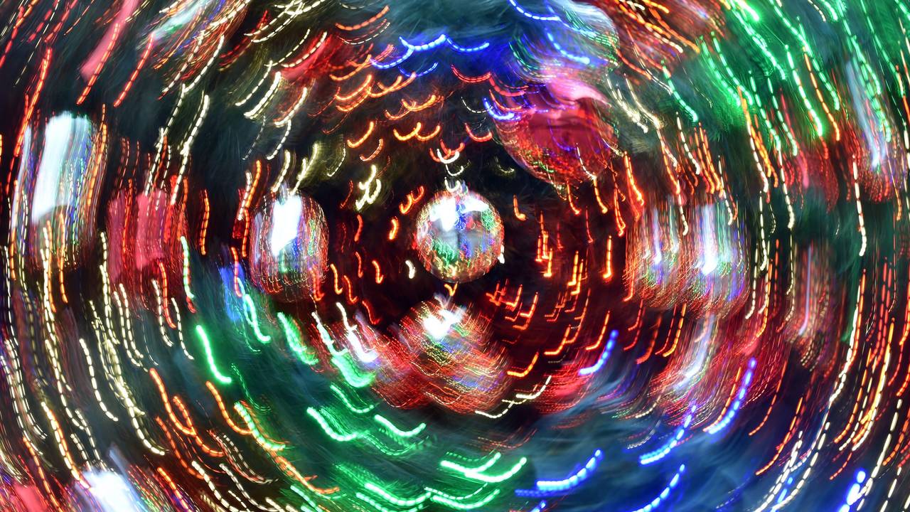 Das Symbolfoto zeigt Weihnachtsbaumkugeln, die sich bewegen. Durch die Langzeitbelichtung entstehen bunte Lichtstreifen.