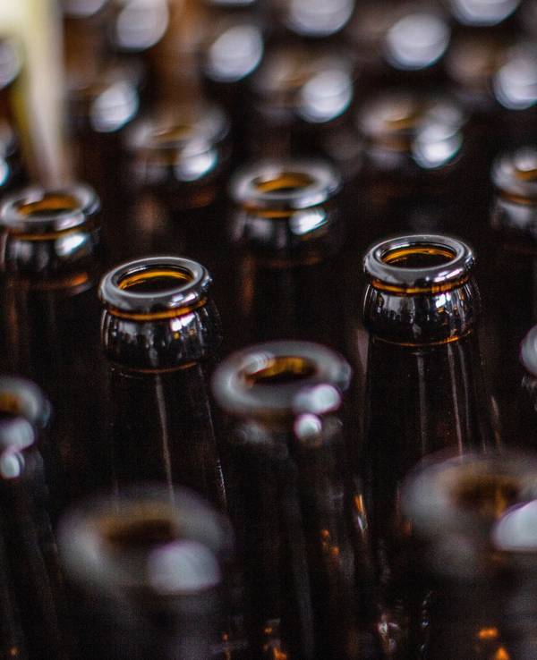 Das Symbolfoto zeigt viele braune Bierflaschen, die nebeneinanderstehen.