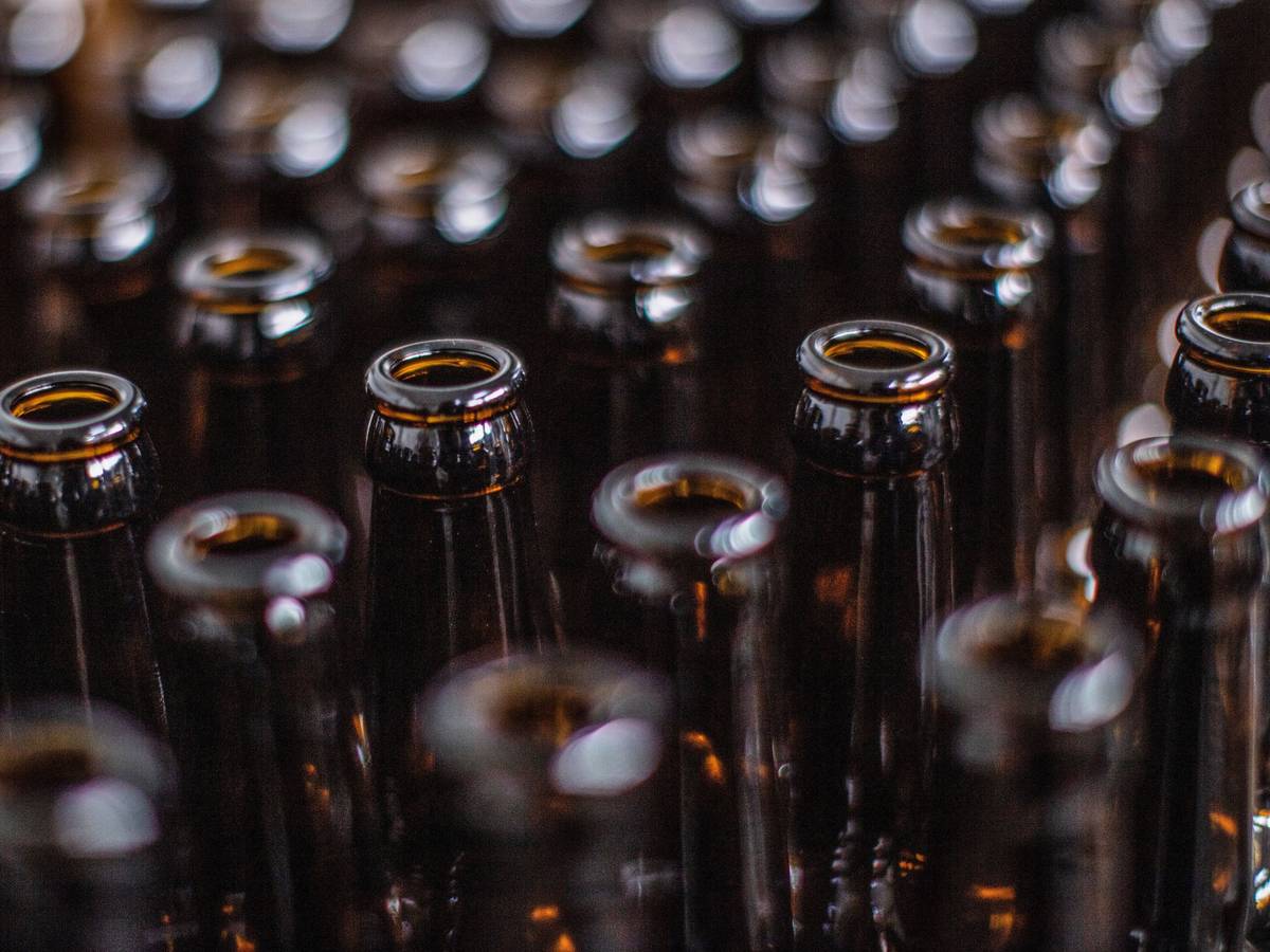 Das Symbolfoto zeigt viele braune Bierflaschen, die nebeneinanderstehen.