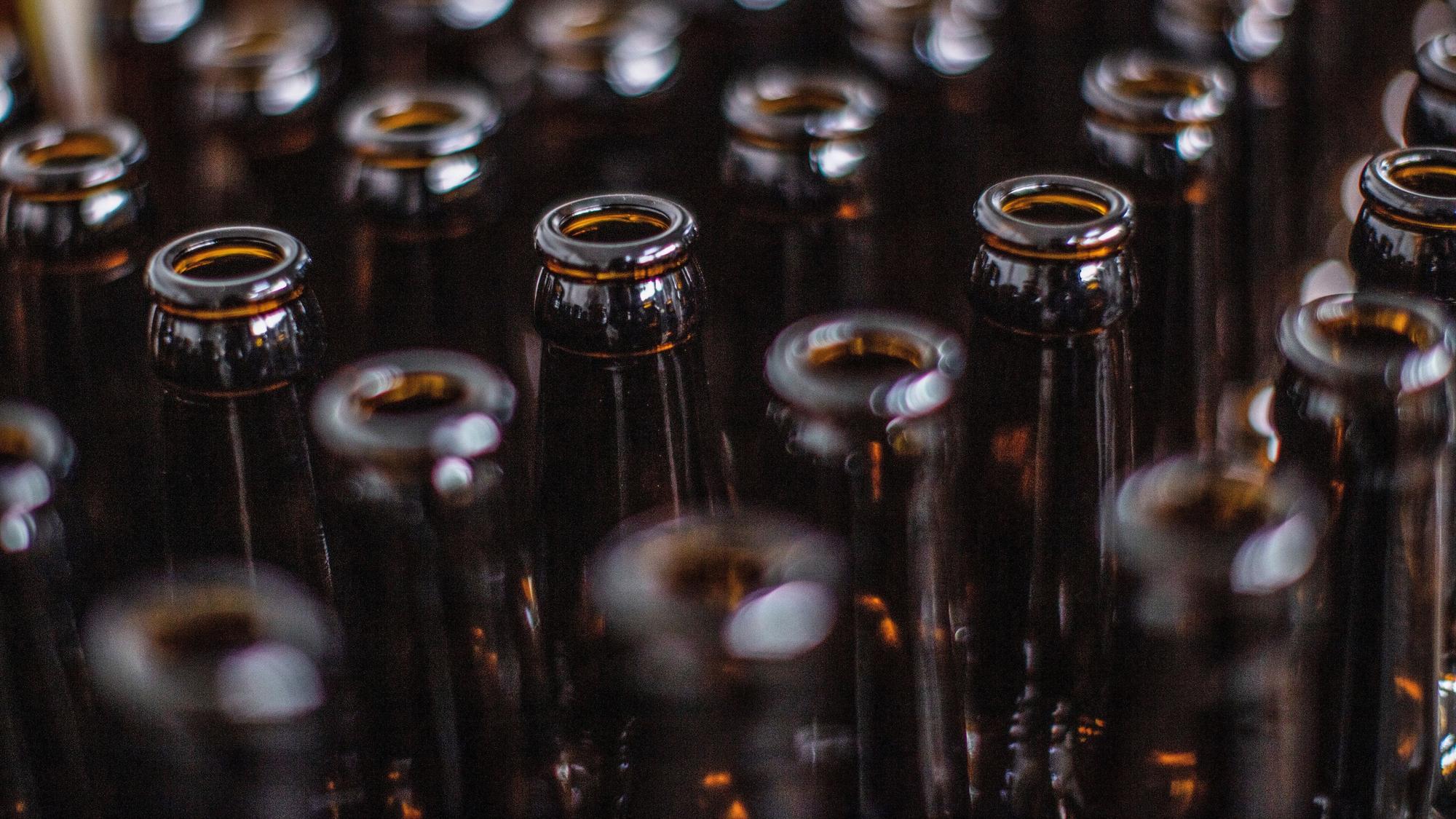 Das Symbolfoto zeigt viele braune Bierflaschen, die nebeneinanderstehen.
