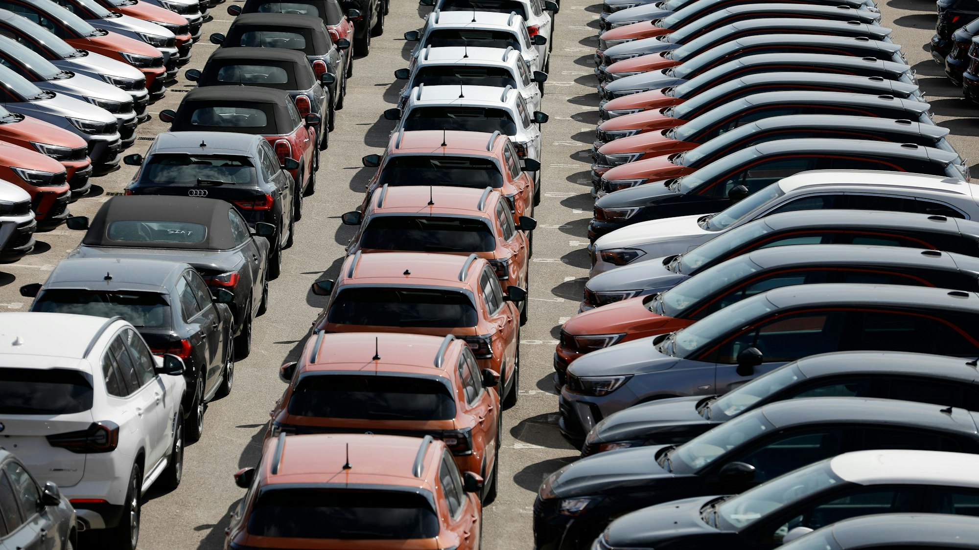 Das Symbolfoto zeigt verschiedenfarbige Mietwagen, die auf einem großen Parkplatz aufgereiht sind.