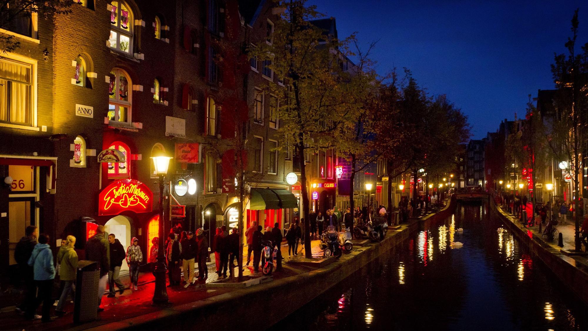 Menschen schlendern am Abend (18. April 2012) an einer Gracht in Amsterdam entlang durch den Rotlichtbezirk De Wallen.