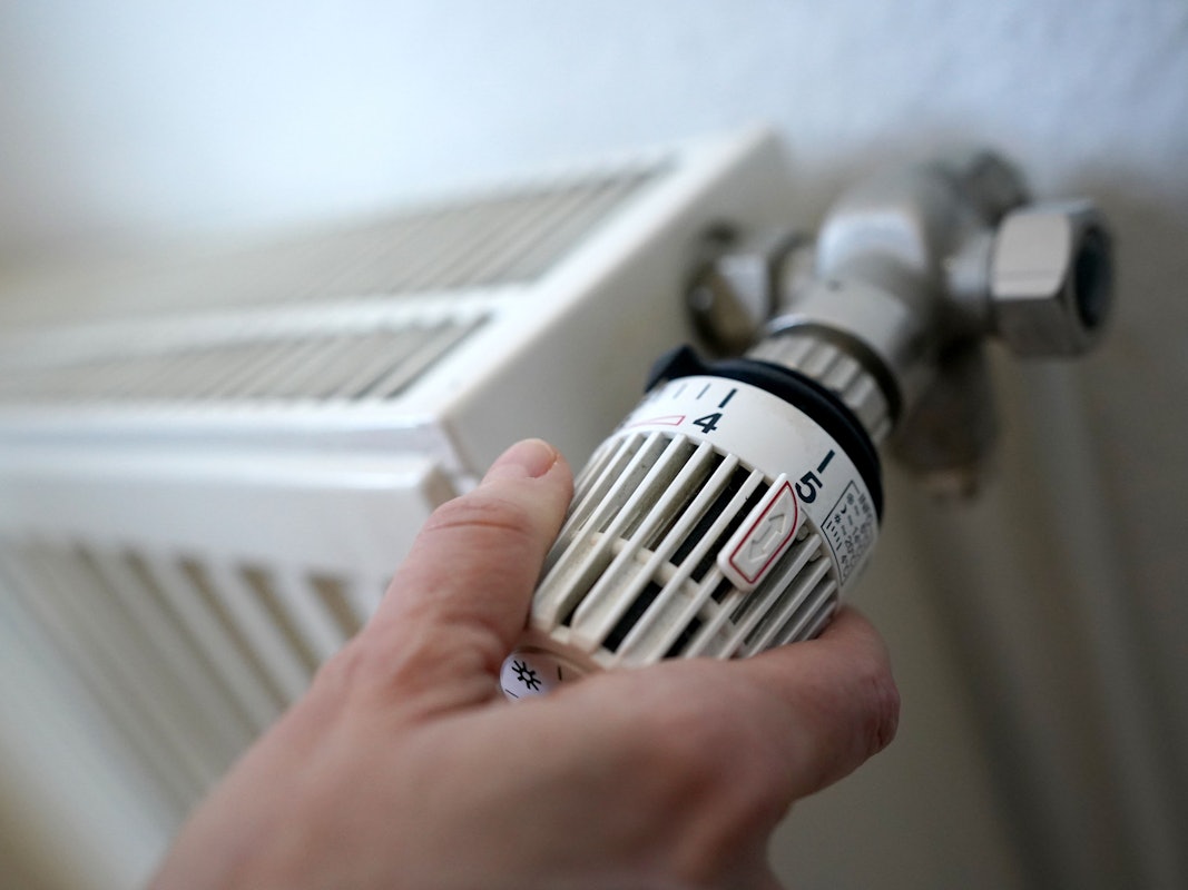 Eine Frau dreht an einem Heizungsthermostat.