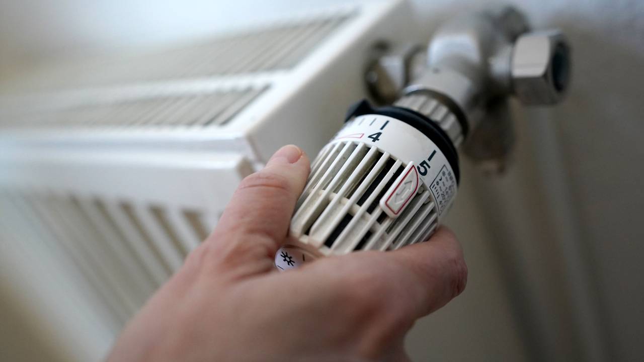 Eine Frau dreht an einem Heizungsthermostat.