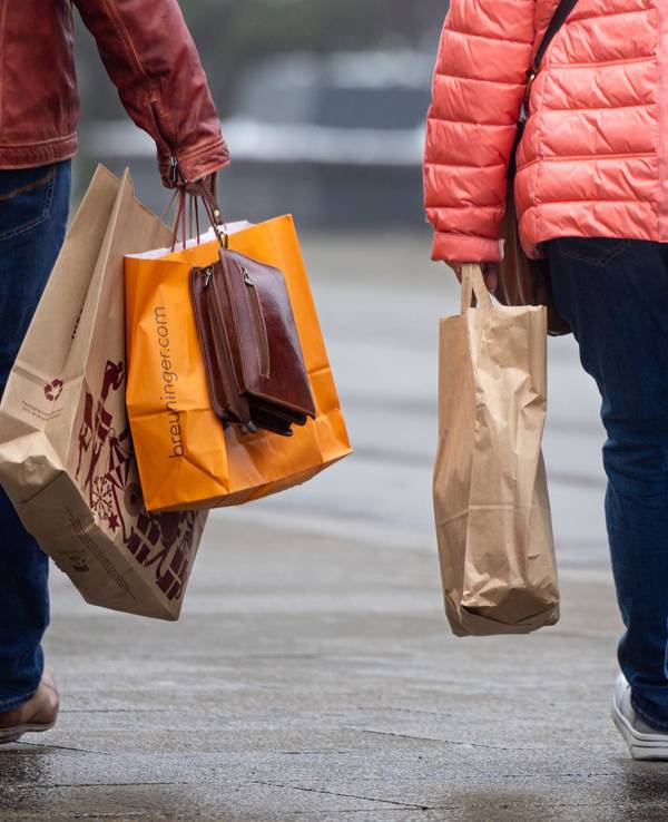 Passanten mit Einkaufstüten in einer Innenstadt.