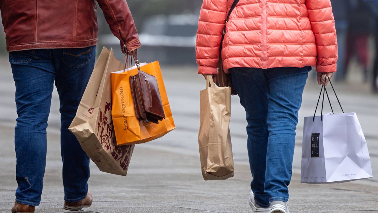 Passanten mit Einkaufstüten in einer Innenstadt.