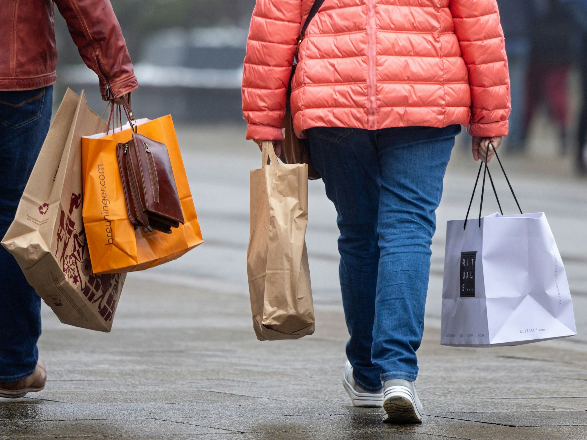 Passanten mit Einkaufstüten in einer Innenstadt.