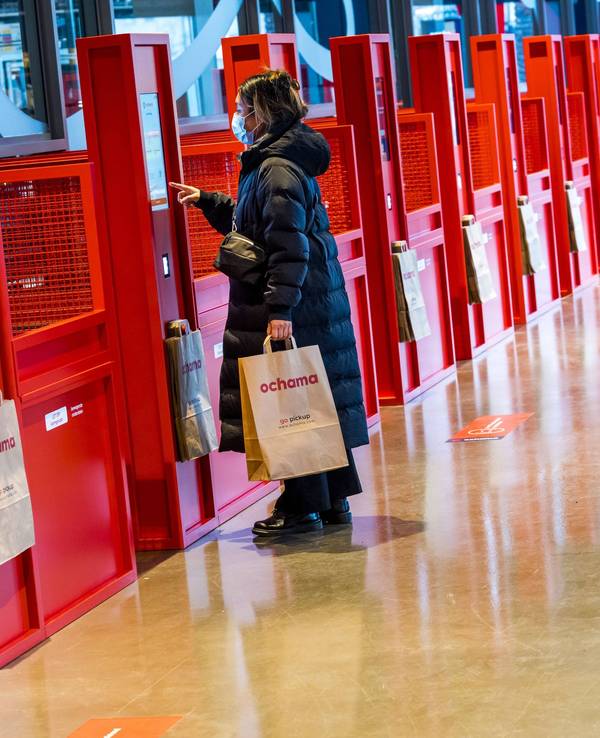 Eine Kundin lässt sich in Rotterdam ihren QR-Code in einer roten Abholstelle des chinesischen Supermarkts Ochama scannen.