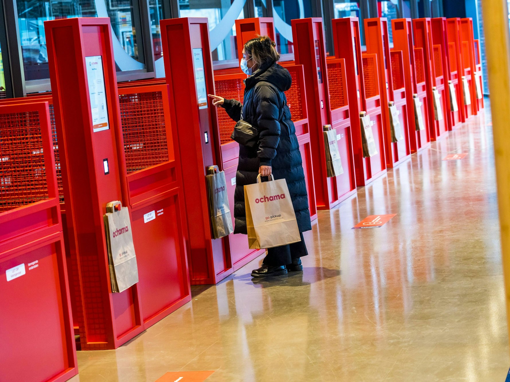 Eine Kundin lässt sich in Rotterdam ihren QR-Code in einer roten Abholstelle des chinesischen Supermarkts Ochama scannen.