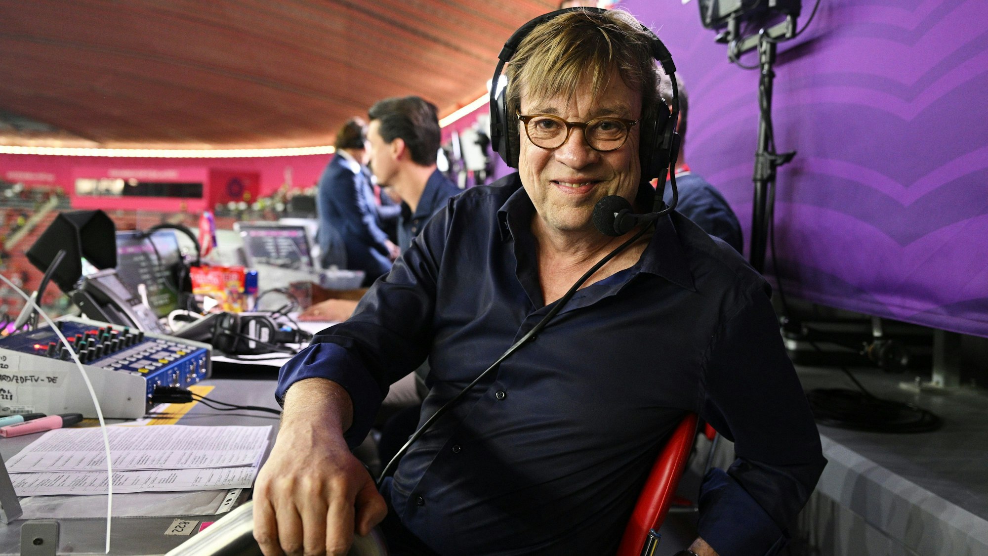 Béla Réthy posiert auf der Kommentatoren-Tribüne für ein Foto bei der WM 2022.