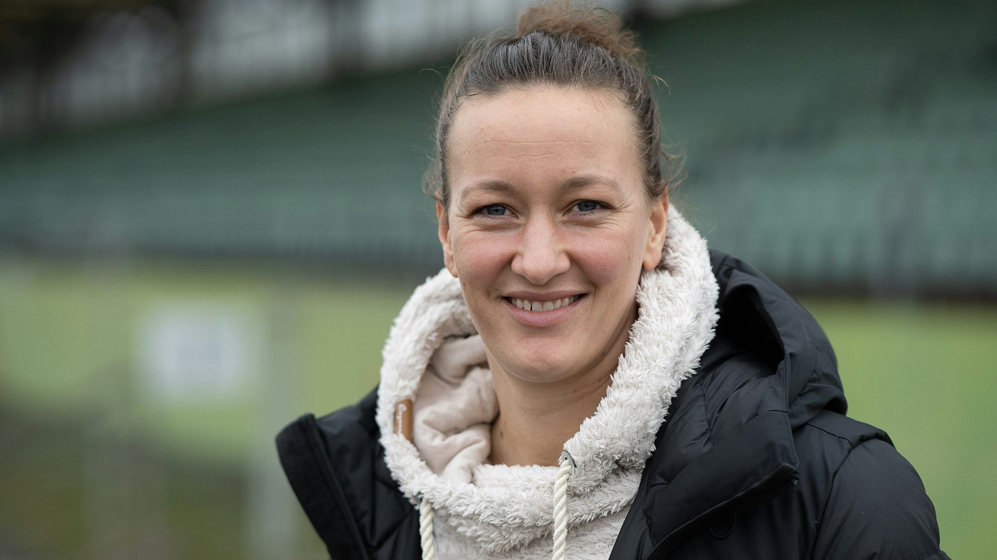 Almuth Schult lächelt im Stadion des VfL Wolfsburg in die Kamera.