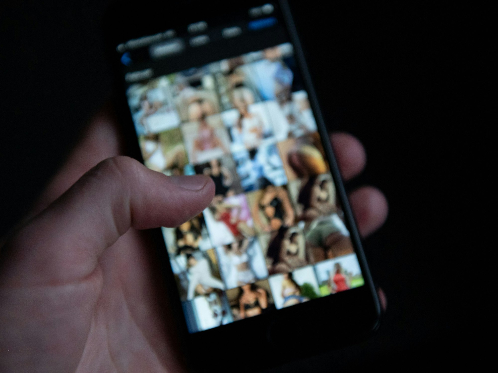 Ein Mann schaut sich auf einem Smartphone pornografische Bilder an.