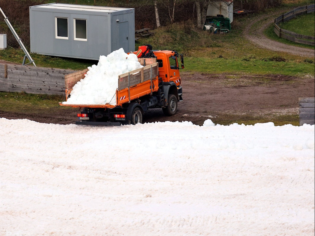 Ein Lastwagen kippt Altschnee in den Schanzenauslauf.