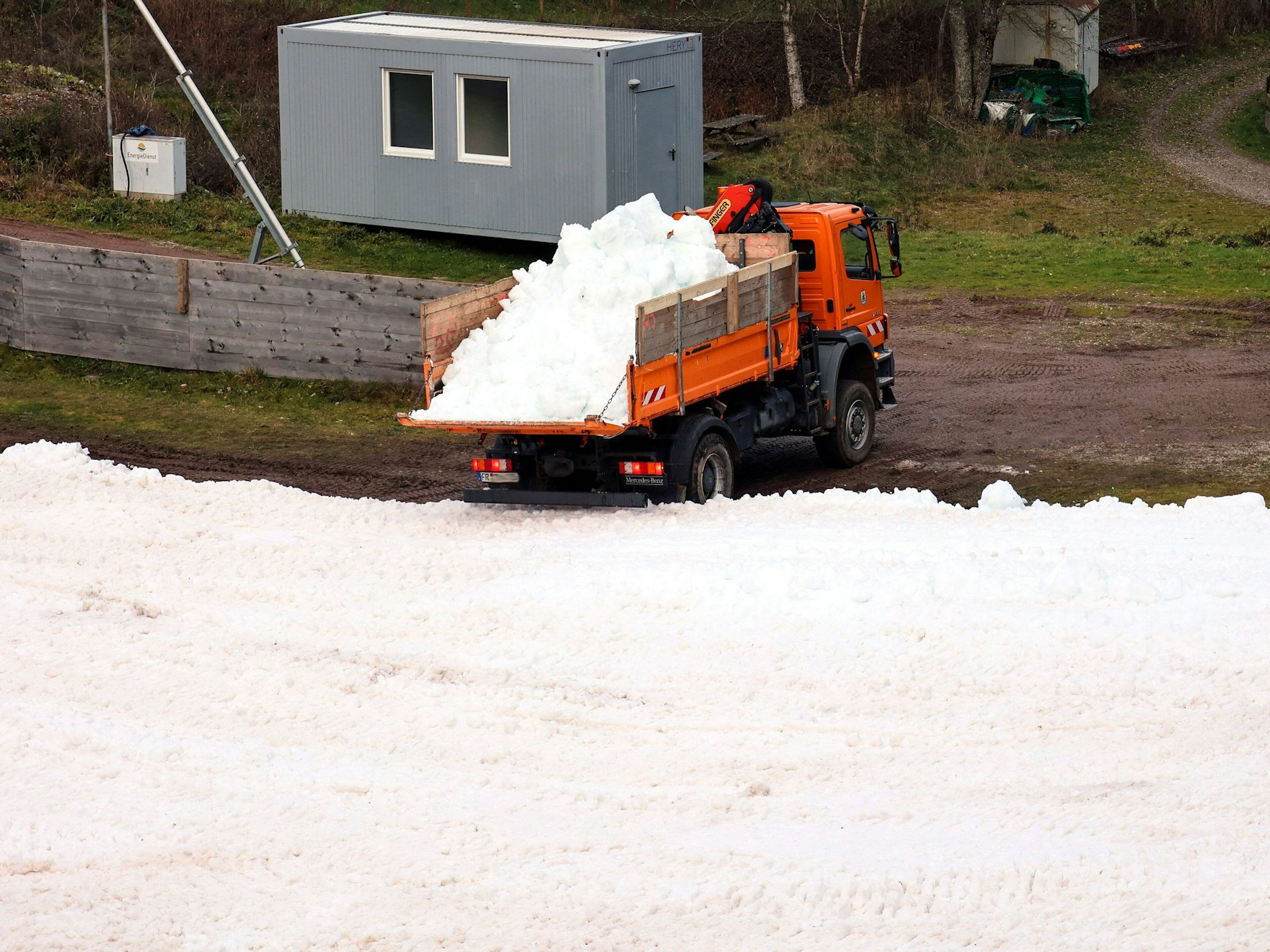 Ein Lastwagen kippt Altschnee in den Schanzenauslauf.