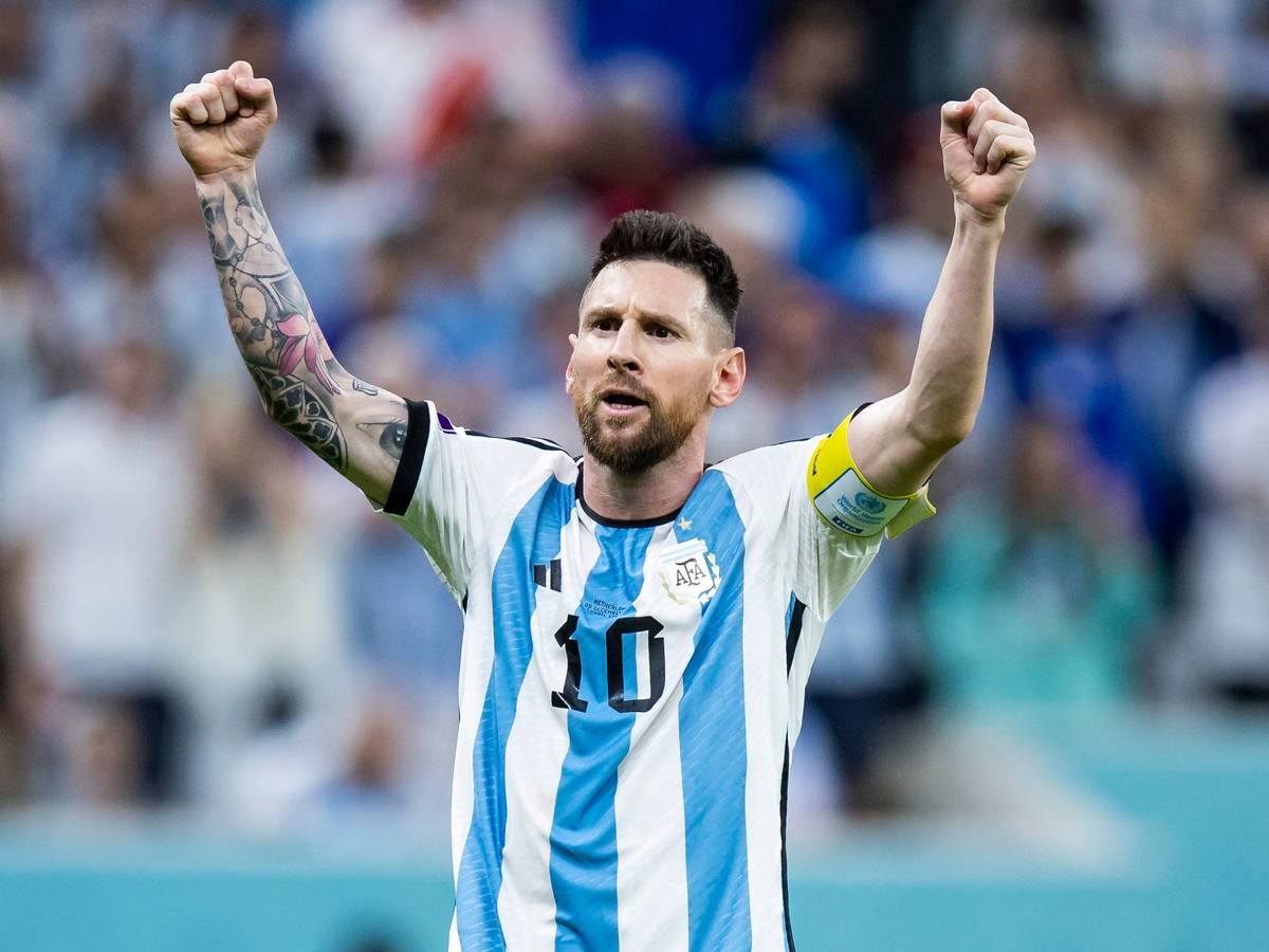 Lionel Messi steht im Trikot von Argentinien mit der Nr. 10 vor der Kurve und reckt beide Fäuste in die Höhe.