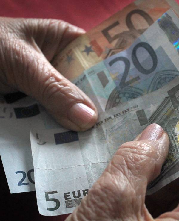 Eine ältere Frau hält verschiedene Euronoten in der Hand.