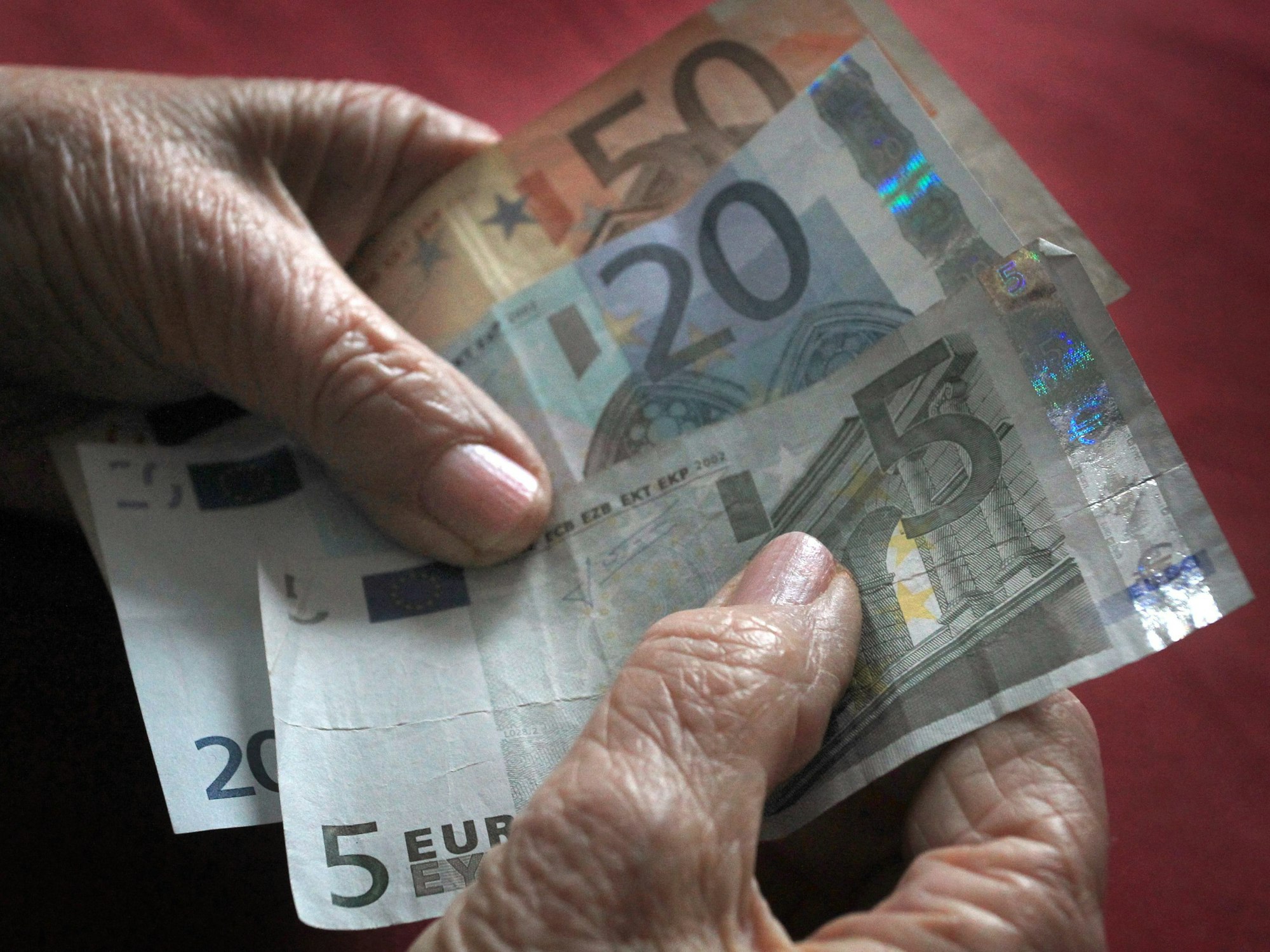 Eine ältere Frau hält verschiedene Euronoten in der Hand.