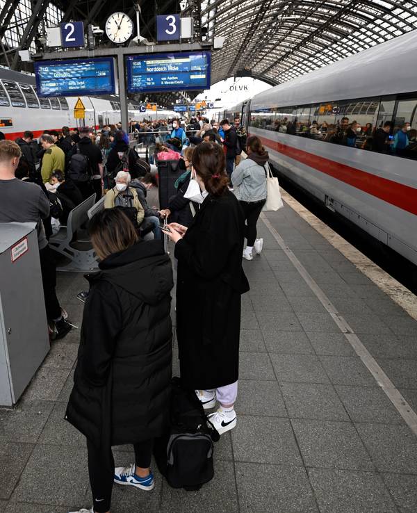 Reisende stehen am Hauptbahnhof und warten auf ihre Weiterfahrt.