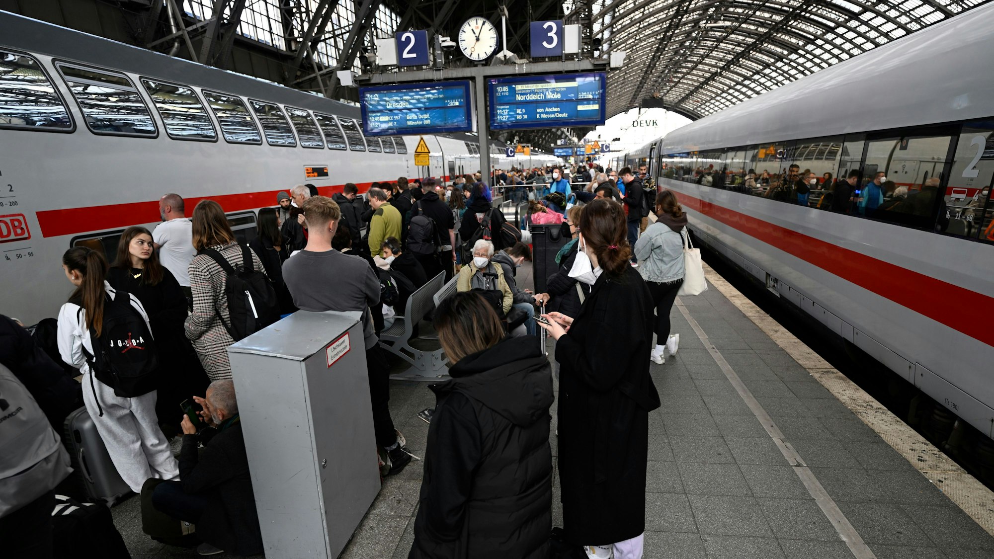 Reisende stehen am Hauptbahnhof und warten auf ihre Weiterfahrt.
