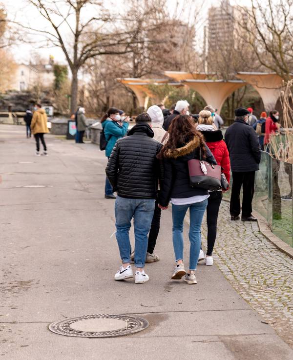 Menschen gehen in dicken Klamotten durch den Kölner Zoo. Rechts ist ein kleineres Gehege zu sehen.