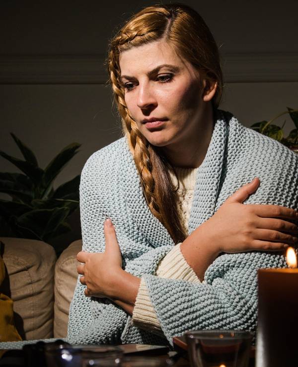 Eine Frau sitzt mit verschränkten Armen auf einer Couch.